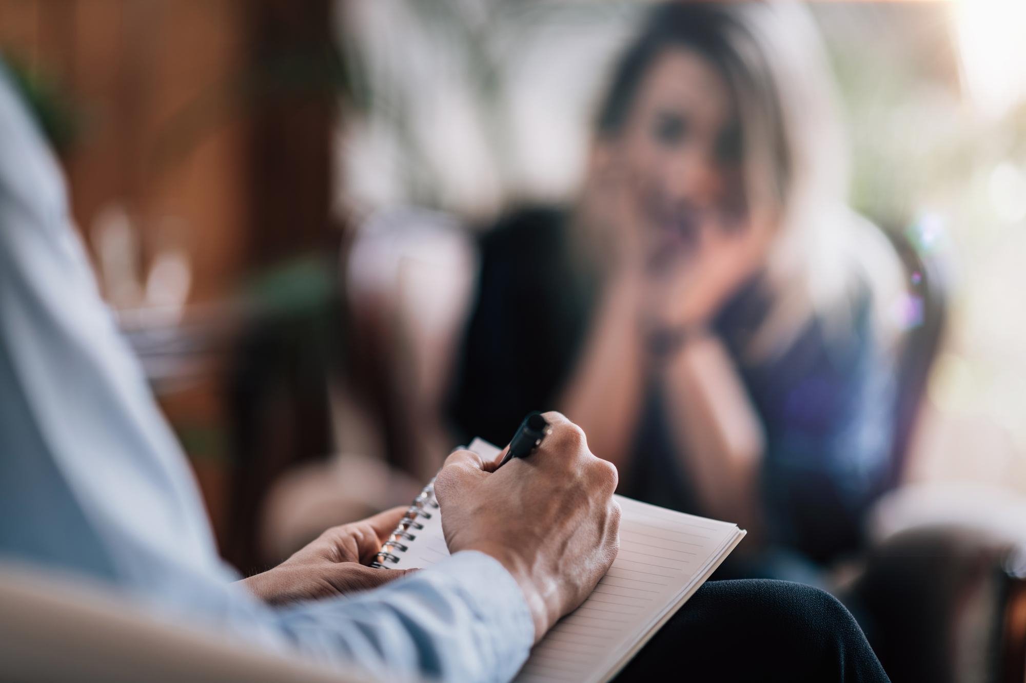 A coach and client reviewing a written weekly plan together at a wooden desk.