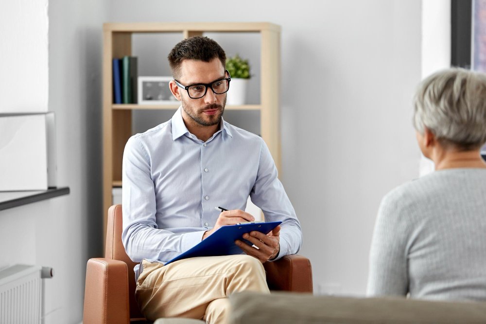 Two chairs facing each other in a softly lit counseling office set up for a psychotherapy session.